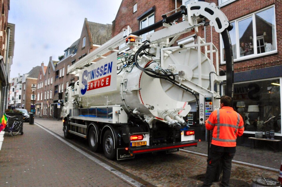 Man met oranje veiligheidskleding ontstopt het riool